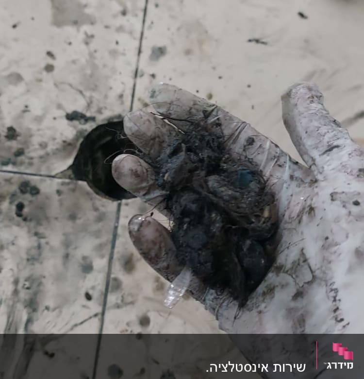 יד עם כפפה מחזיקה לכלוך שהוצא מצינור